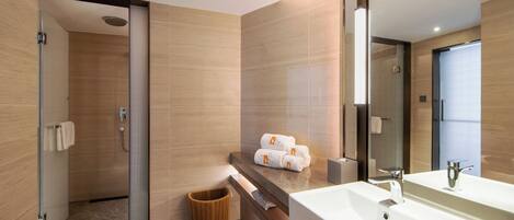 A modern bathroom with a large mirror, a sink, and a shower area.