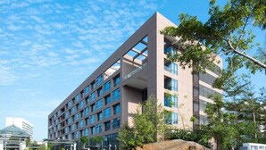 Un moderno edificio de hotel con varios pisos, amplias ventanas y un jardín bien cuidado.