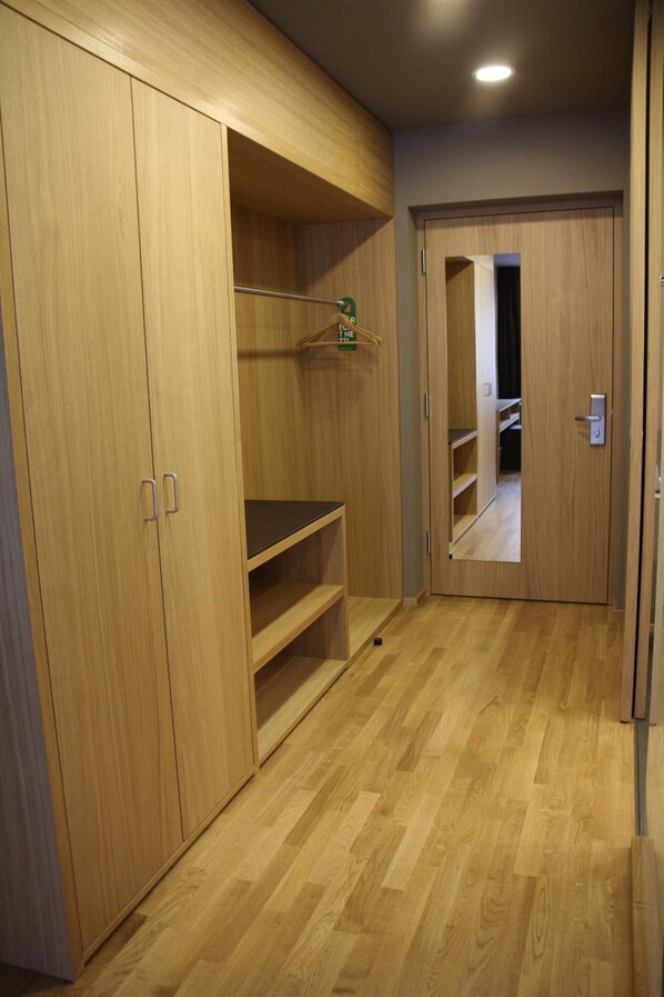 A hallway with wooden flooring and a wardrobe with open doors.