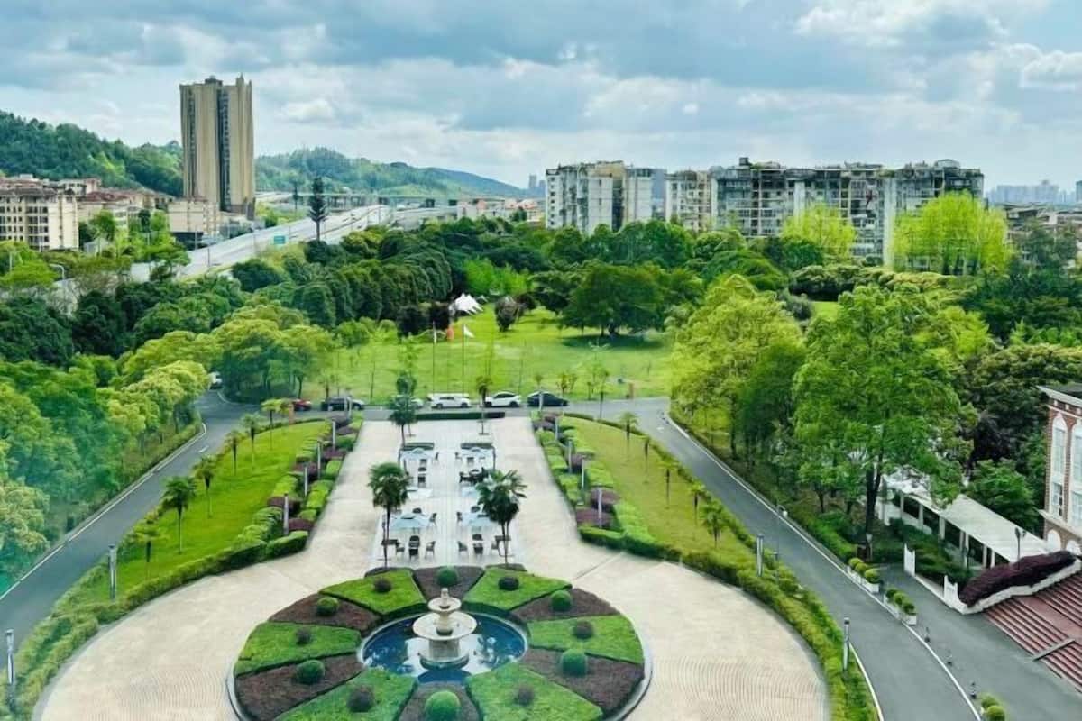 A park with a fountain, pathways, and surrounding greenery.