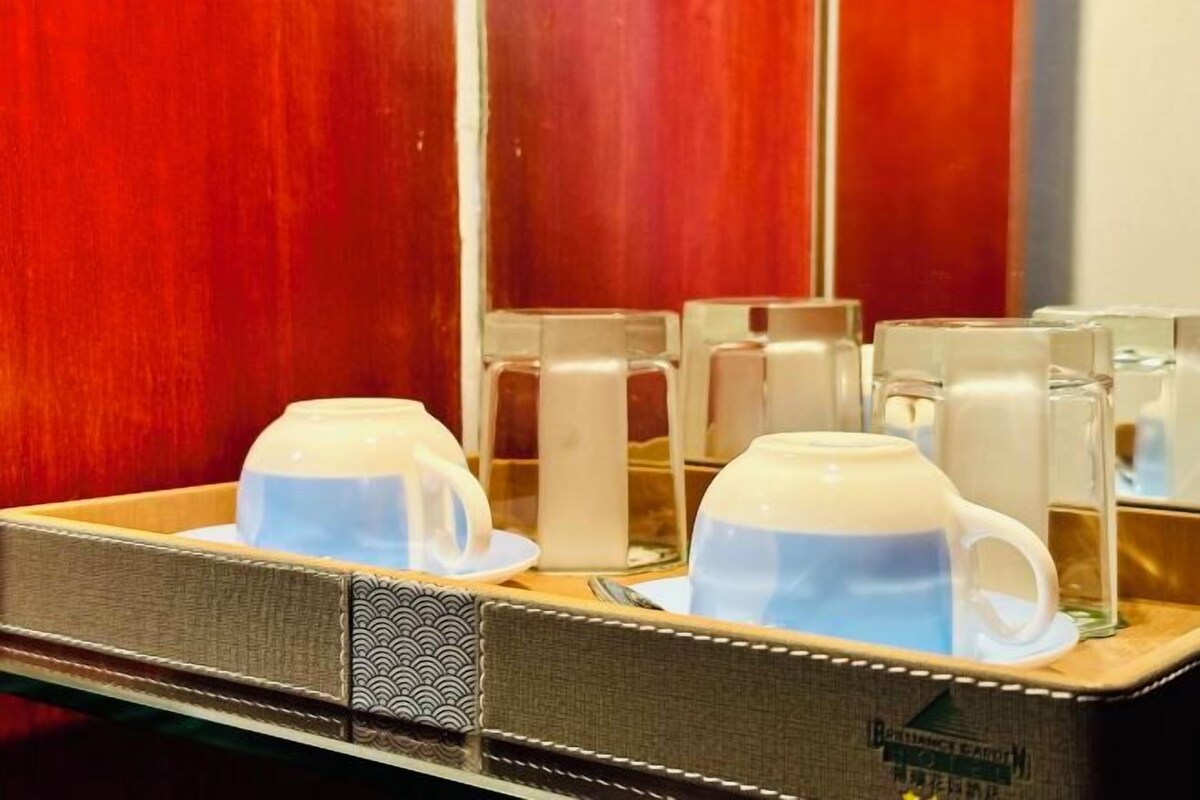 A tray with white cups and a teapot, reflecting in a mirror.