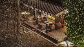 A cozy outdoor seating area with a wooden deck, cushioned seating, and a small table. - Brilliance Garden Hotel (CHENGDU)