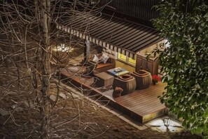 A cozy outdoor seating area with a wooden deck, cushions, and a table. - Brilliance Garden Hotel (CHENGDU)