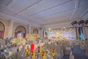A banquet hall with round tables, chairs, and floral centerpieces. - Brilliance Garden Hotel (CHENGDU)