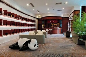 A lobby with a reception desk, seating area, and a wall of red storage boxes. - Brilliance Garden Hotel (CHENGDU)