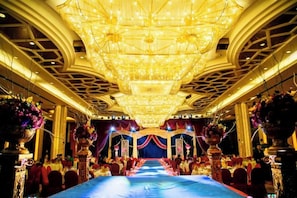 A banquet hall with a long table, chandeliers, and floral decorations. - Brilliance Garden Hotel (CHENGDU)
