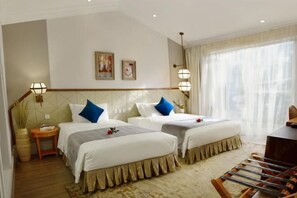 A hotel room with two beds, a small table, a chair, and a large window with sheer curtains. - Brilliance Garden Hotel (CHENGDU)