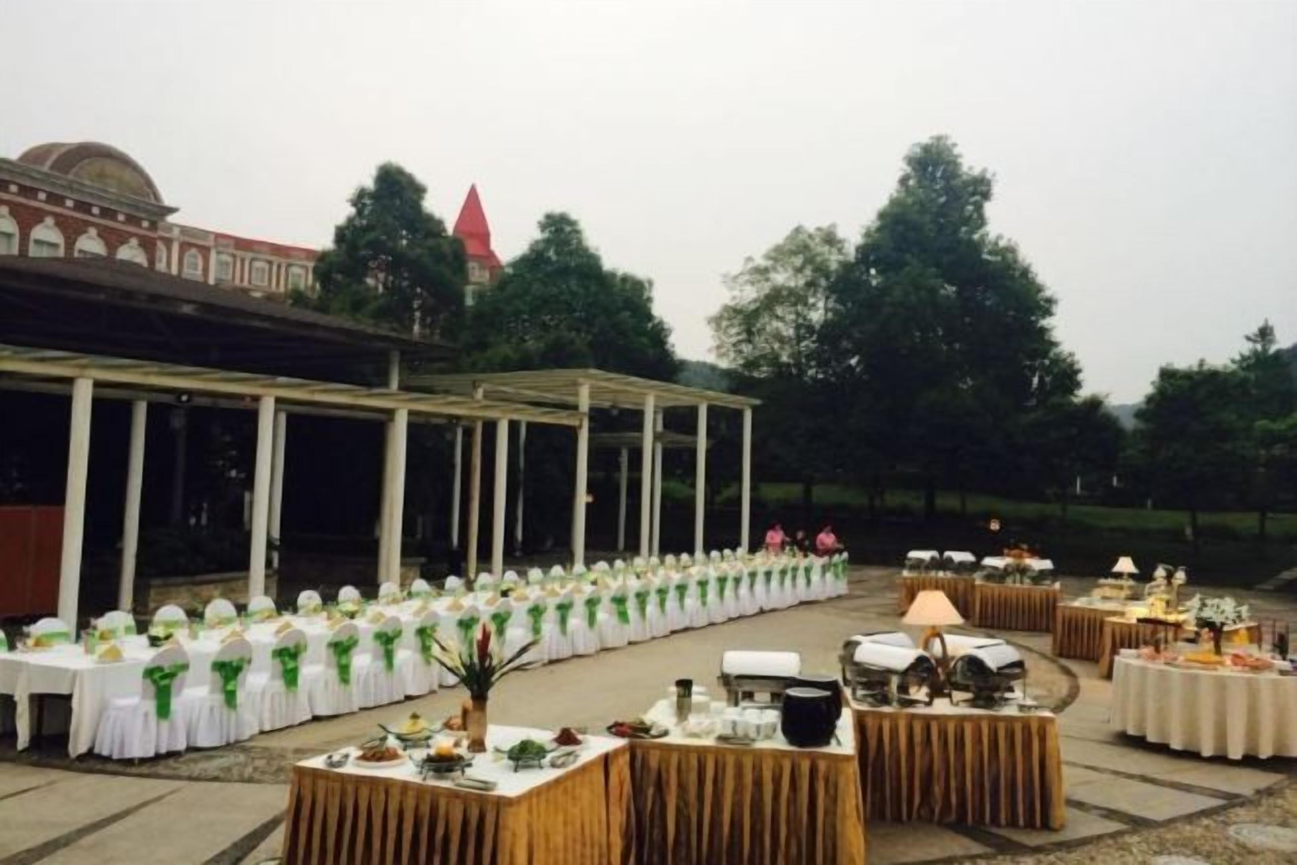 An outdoor event space with tables set for a reception, a covered area with columns, and a building with a dome in the background.