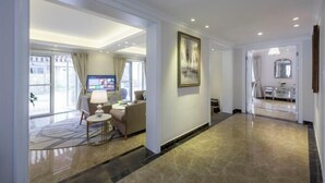 A hotel lobby with a marble floor, a seating area with a table and chairs, a television, and a framed artwork on the wall. - Brilliance Garden Hotel (CHENGDU)