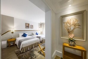 A hotel room with two beds, a wooden console table with a vase, and a large floral painting on the wall. - Brilliance Garden Hotel (CHENGDU)