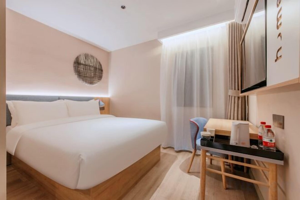 Una habitación de hotel con cama, escritorio, silla y televisión.