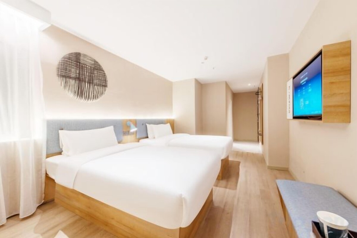 Habitación de hotel moderna con una cama grande, un televisor montado en la pared y un cabecero de madera.