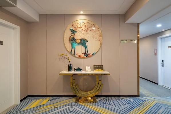 Zona de recepción con una obra de arte en la pared que representa un ciervo, un mostrador de recepción y piso alfombrado.