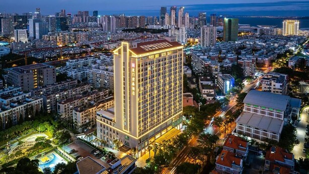 Ein Hochhaus-Hotel mit zahlreichen Stockwerken, umgeben von einer dichten Stadtlandschaft mit weiteren Gebäuden und Straßen.