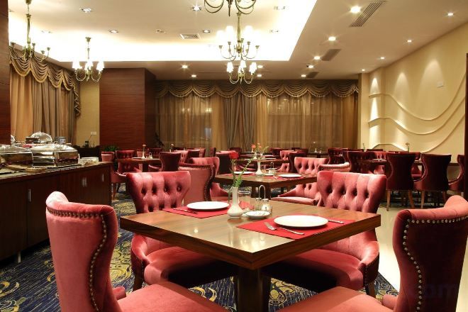 Un comedor de hotel con varias mesas y sillas, un bufé y candelabros.