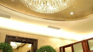 A grand chandelier, a large mirror, and a potted plant in a hotel lobby. - Jinyan Hotel (SHANGHAI)