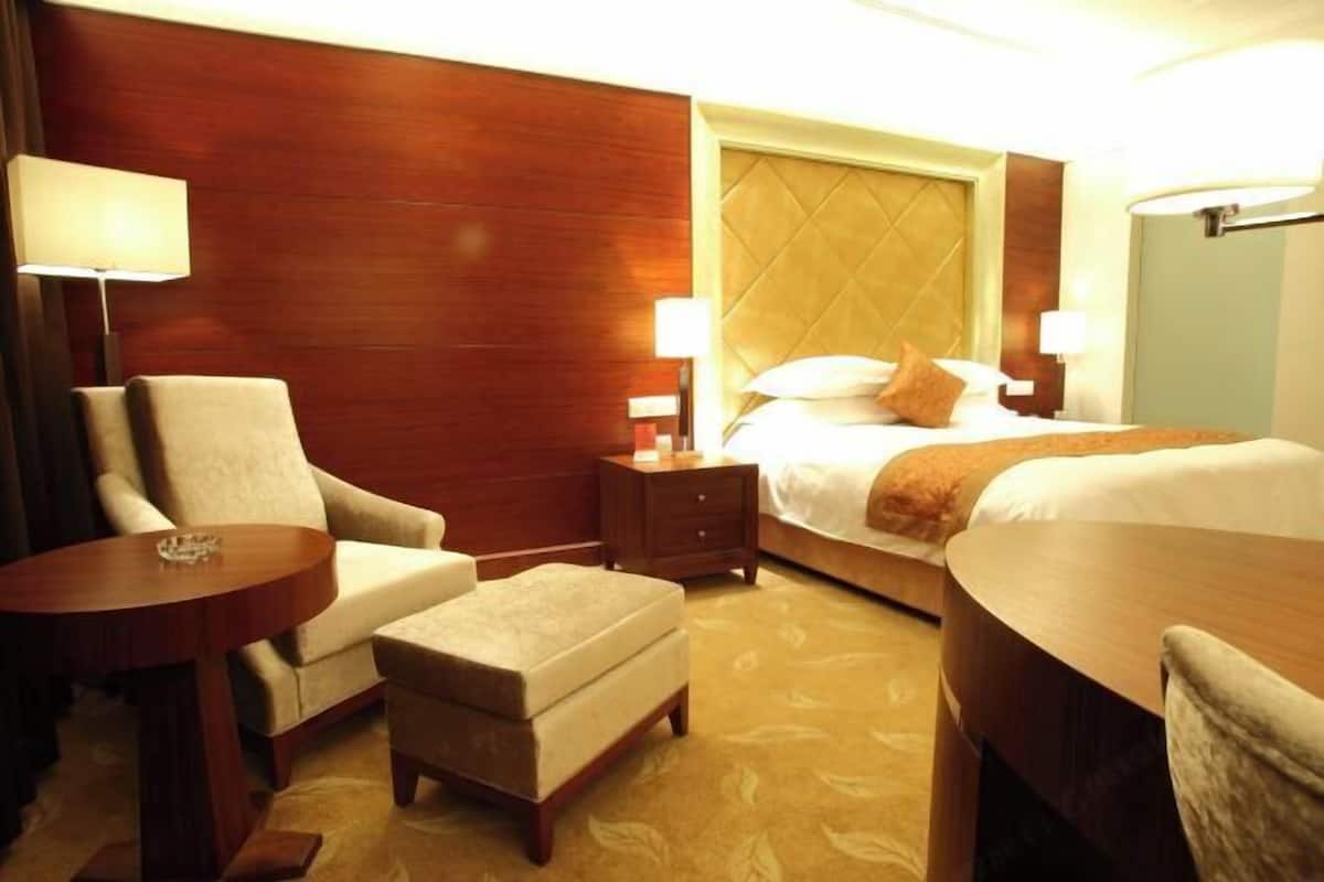 A hotel room with a bed, a chair, a small table, and a nightstand.