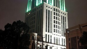 A tall building with a prominent corner section and a large windowed facade. - Jinyan Hotel (SHANGHAI)