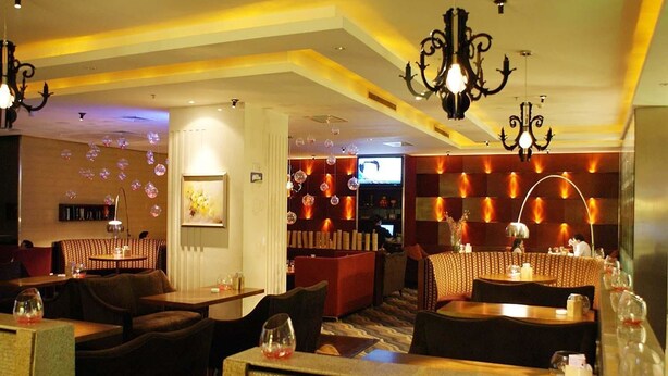 A restaurant with a cozy seating area, a bar, and a television screen. - Starshine Hotel (Shenzhen)