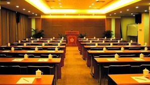A conference room with rows of tables, each with a teapot and a notepad. - Starshine Hotel (Shenzhen)
