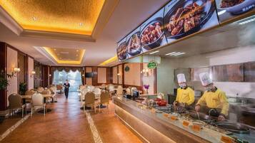 A hotel restaurant with a long counter, multiple seating areas, and a large menu display.