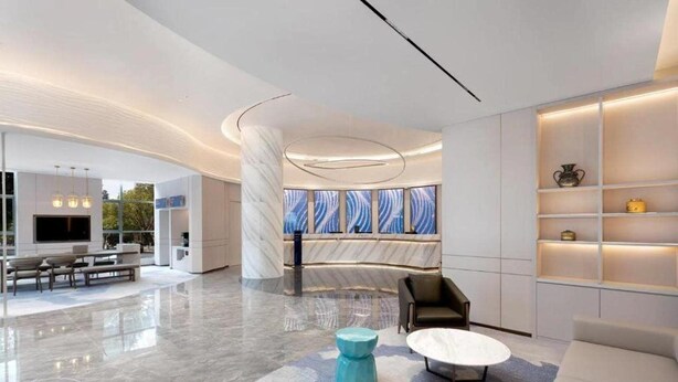 A modern lobby with a curved marble column, a seating area with sofas and a coffee table, and a wall with shelves and decorative items. - Vienna Hotel (Shanghai)