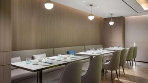 A modern dining area with a long table, multiple chairs, and pendant lighting. - Vienna Hotel (Shanghai)