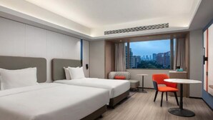 A hotel room with two beds, a small table, a chair, and a view of the cityscape. - Vienna Hotel (Shanghai)