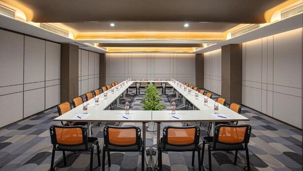 A conference room with a long table, chairs, and a plant in the center. - Vienna Hotel (Shanghai)