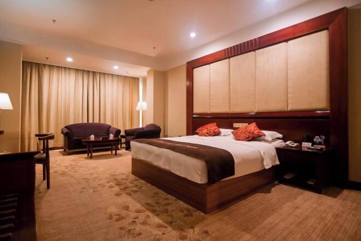 Una habitación de hotel con una cama grande, un escritorio, una silla, una lámpara y una mesita de noche.