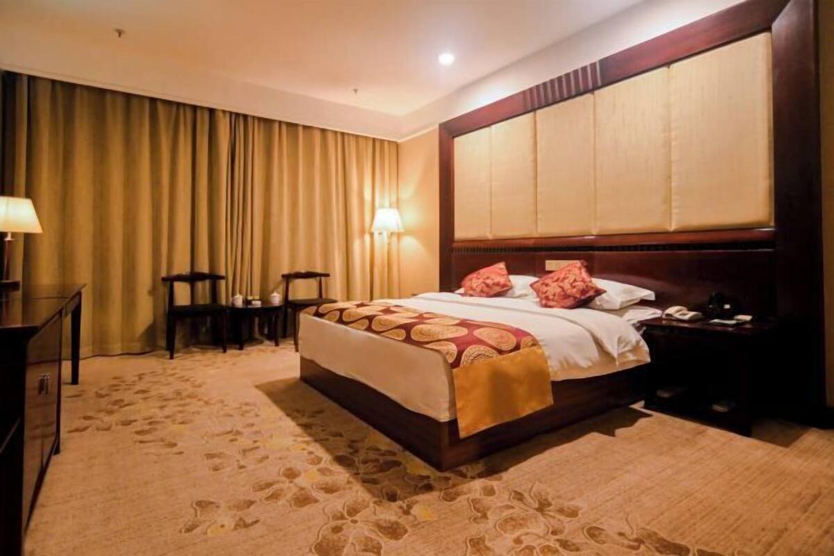 Habitación de hotel con una cama grande, un escritorio, una silla y una mesita de noche.