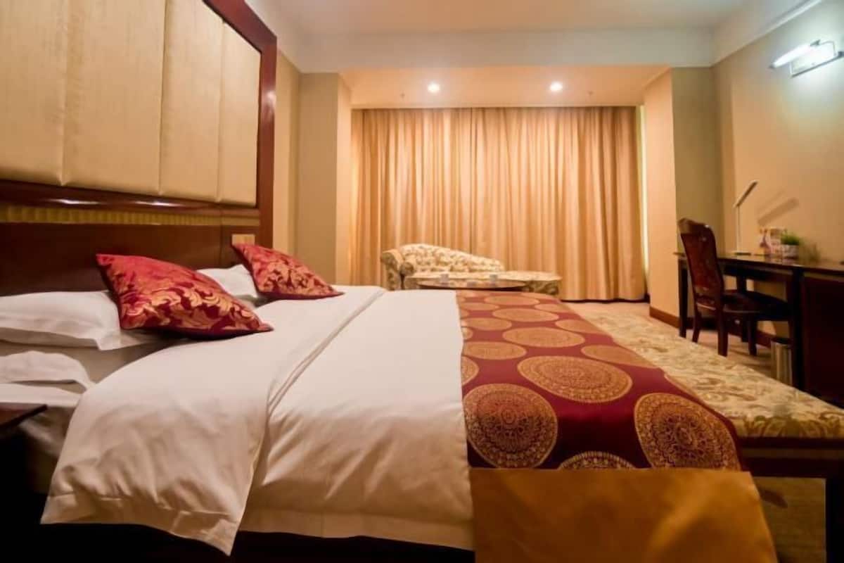 Una habitación de hotel con una cama, una silla, un escritorio y una cortina.