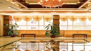 A lobby with a glass floor, a sofa, two potted plants, and a chandelier. - Mizhou Hotel (ZHUCHENG)