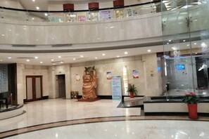 A spacious lobby with a large statue, a reception desk, and a glass railing. - Mizhou Hotel (ZHUCHENG)