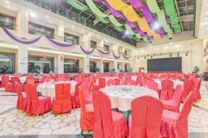 A banquet hall with round tables and chairs, a stage, and a balcony. - Mizhou Hotel (ZHUCHENG)