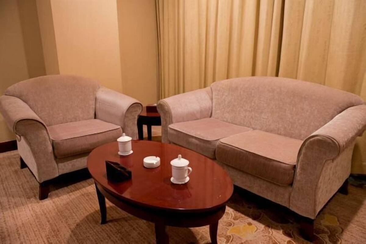 Una habitación con dos sofás color beige, una mesa de centro de madera y una mesita auxiliar.