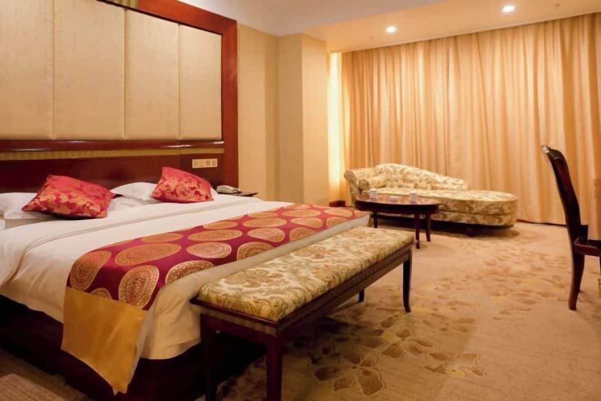 Una habitación de hotel con una cama, un banco, una silla y un sofá.