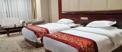 A hotel room with two beds, a sofa, a coffee table, and a large window with curtains.