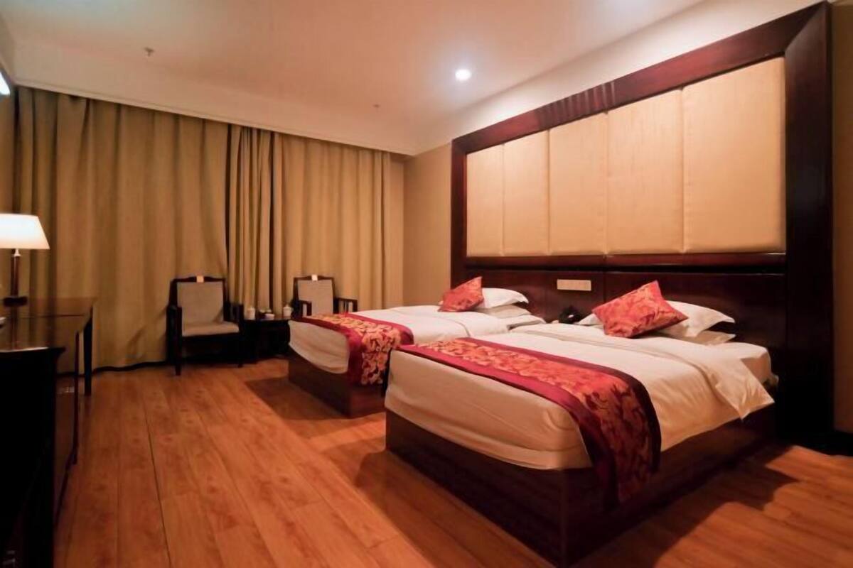 Habitación de hotel con dos camas, un escritorio y una silla.