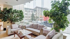 A modern interior with a sofa set, a coffee table, and large windows offering a view of the street. - Mizhou Hotel (ZHUCHENG)