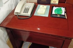 A wooden desk with a telephone, a book, a wallet, and a pen. - Mizhou Hotel (ZHUCHENG)