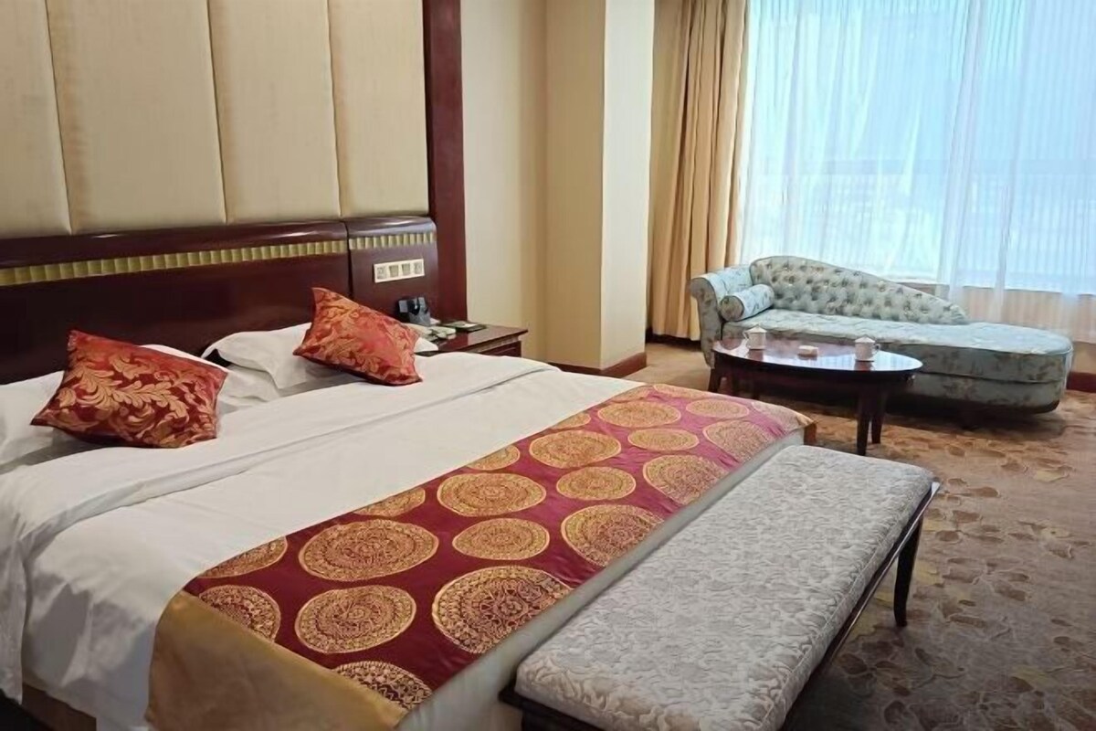 A hotel room with a large bed, a sofa, and a small table.