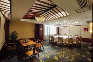 Un comedor de hotel con una gran mesa redonda, varias sillas y suelo alfombrado.
