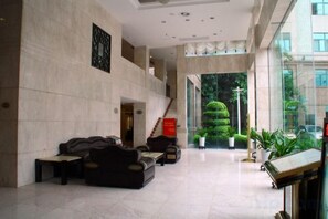 A spacious lobby with a high ceiling, a staircase, and a view of a well-maintained garden. - Royal Prince Hotel (Quanzhou)