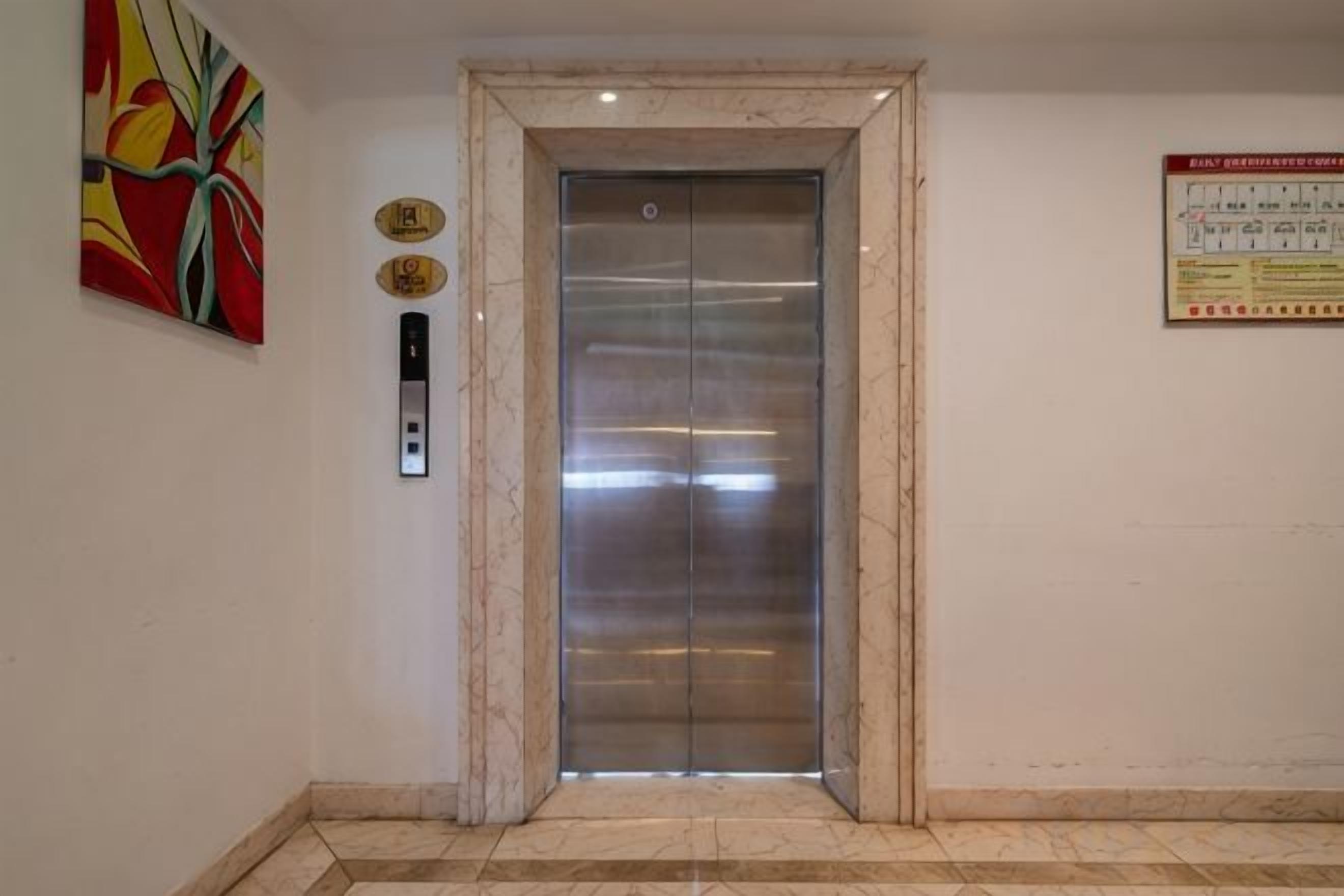 Un ascenseur doté d’un cadre en marbre, d’un panneau de commande et d’un panneau d’avertissement de sécurité fixé au mur.