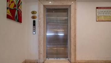An elevator with a marble frame, a control panel, and a safety sign on the wall.