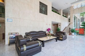 A lobby with a reception desk, two sofas, a coffee table, and a staircase. - Royal Prince Hotel (Quanzhou)