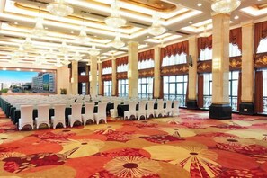 A large conference room with rows of chairs, a carpeted floor, and a cityscape view through large windows. - Royal Prince Hotel (Quanzhou)