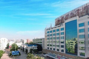 A multi-story building with a modern architectural design, featuring a large glass facade and a prominent sign on the top. - Royal Prince Hotel (Quanzhou)