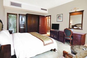A hotel room with a large bed, a desk, a chair, a television, and a wardrobe. - Royal Prince Hotel (Quanzhou)